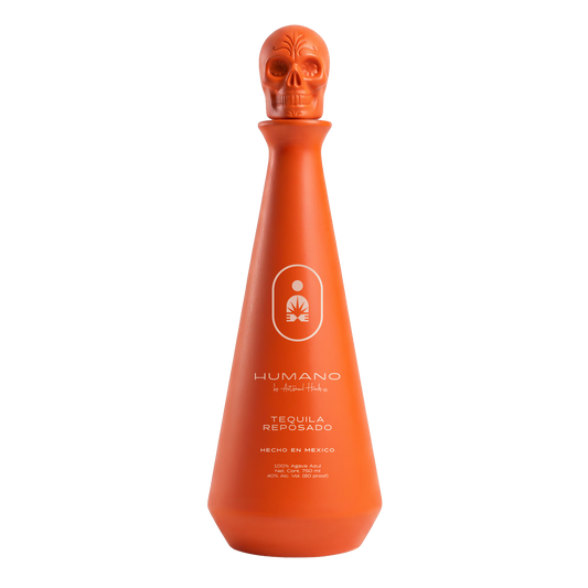 An orange tequila bottle with a skull-shaped stopper, featuring the HUMANO brand logo and text on the front, set against a plain white background.